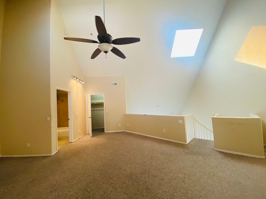 a large empty living room with a ceiling fan