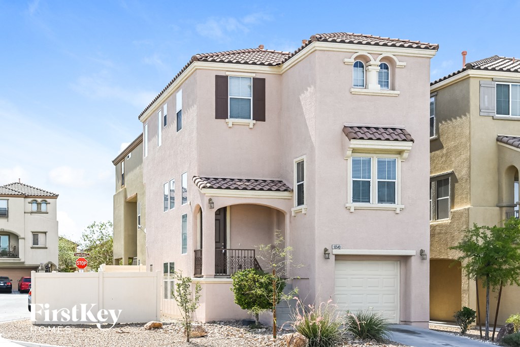 a beige house with two garage doors and a driveway