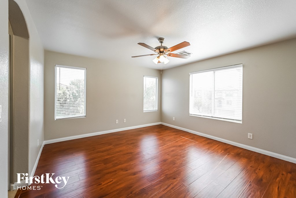 an empty living room with wood floors and a ceiling fan