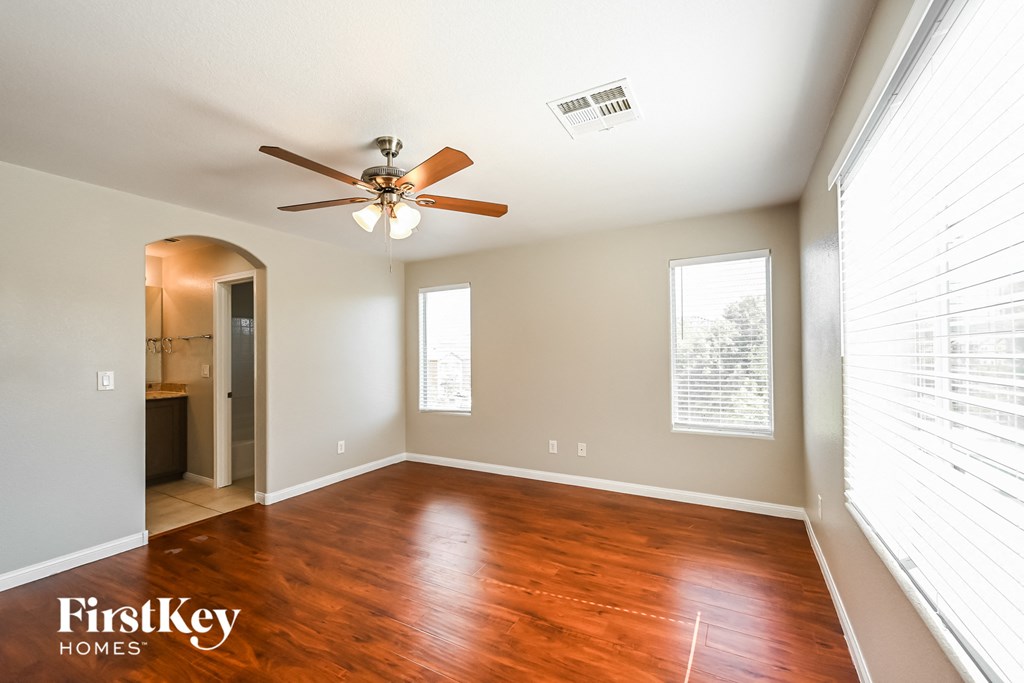 an empty living room with wood floors and a ceiling fan