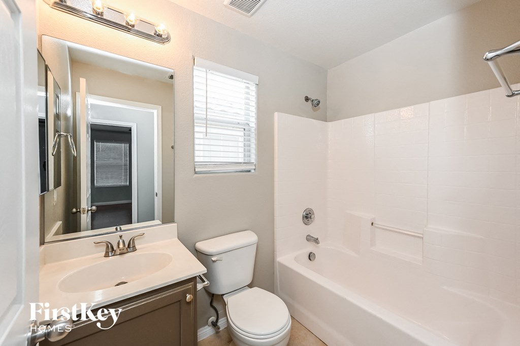 a bathroom with a toilet sink and tub and a mirror