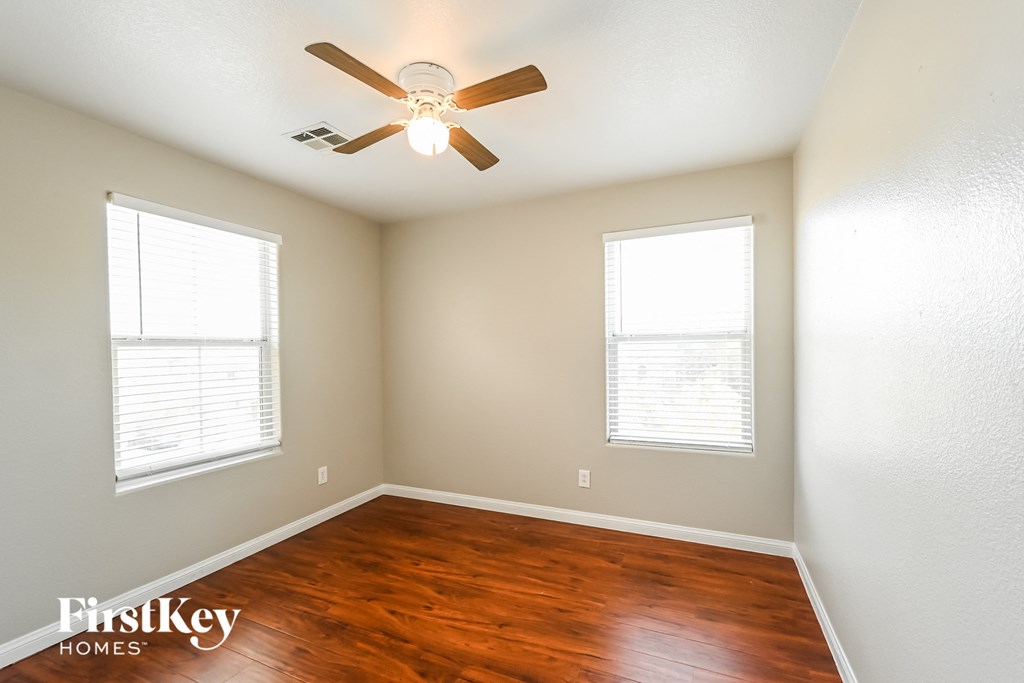 the master bedroom has a hard wood floor and a ceiling fan