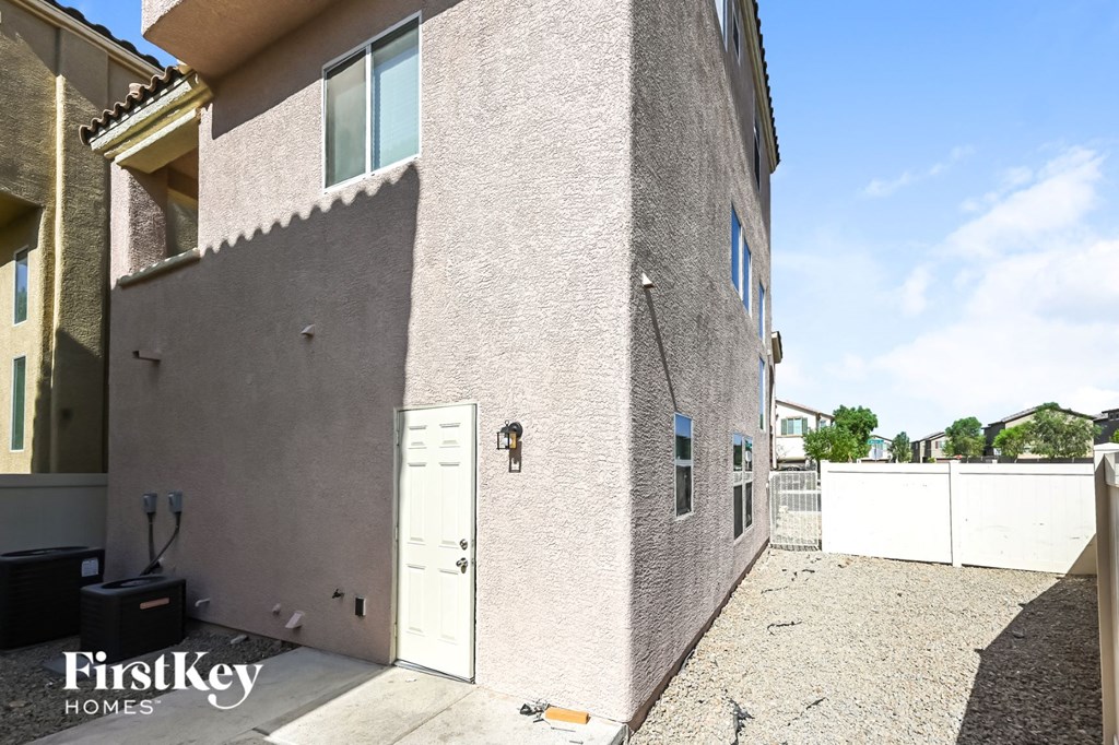 the side of a brick house with a white door and a white fence
