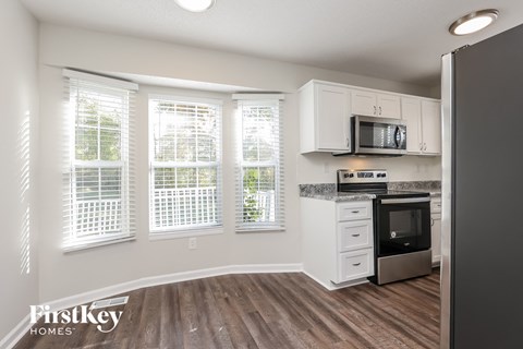 a kitchen with white cabinets and a stove and a window