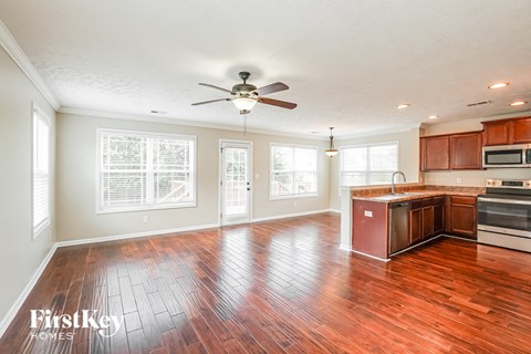 A spacious kitchen and living room with wooden floors and a ceiling fan.