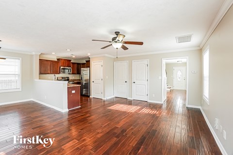 A spacious room with wooden floors and a ceiling fan.
