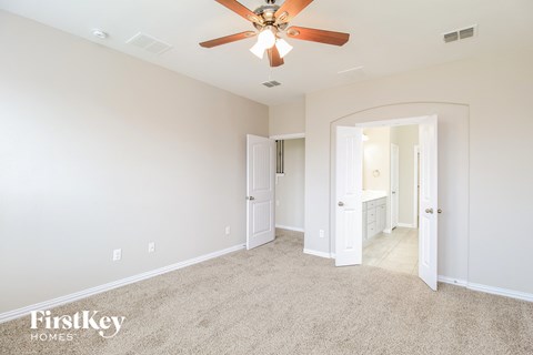 a master bedroom with carpet and a ceiling fan