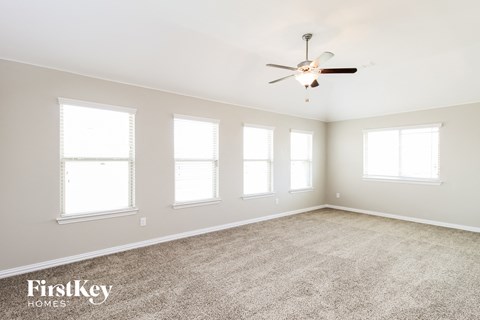 a living room with four windows and a ceiling fan