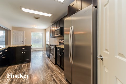 A kitchen with a stainless steel refrigerator and wooden floors.