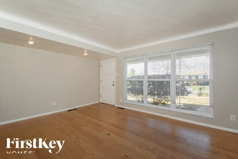 A room with wooden floors and a large window with blinds.