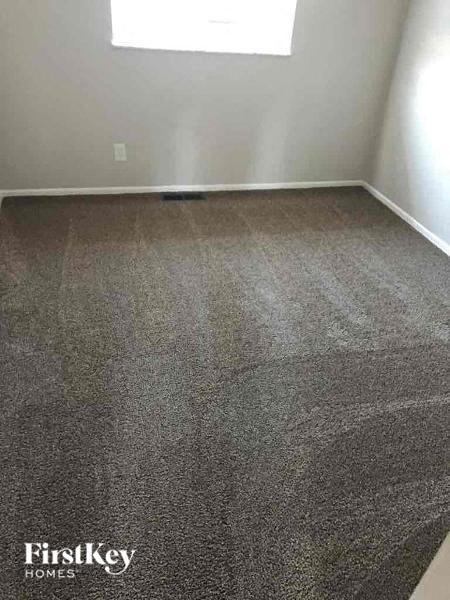 A room with a grey carpet and a window.
