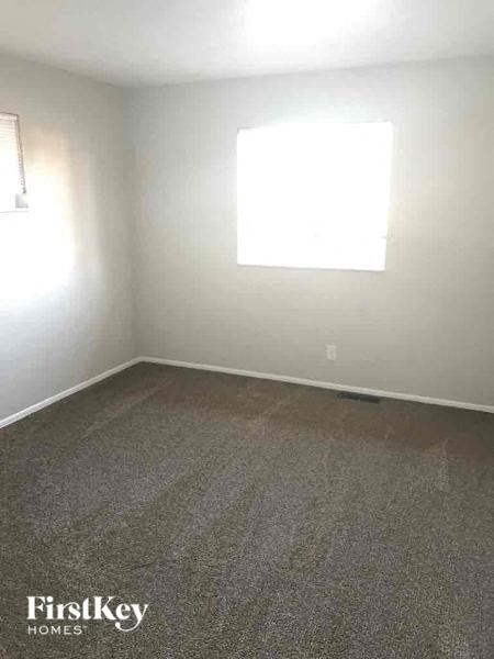 A room with a grey carpet and a window.