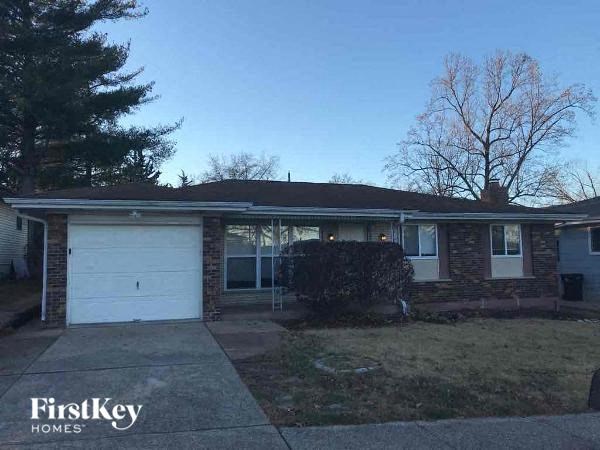 A house with a garage and a tree in front of it.