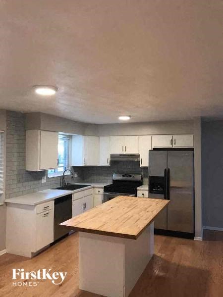 A kitchen with a wooden counter top and stainless steel appliances.