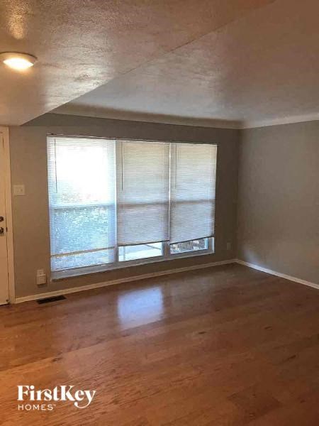 A room with wooden floors and a large window with blinds.