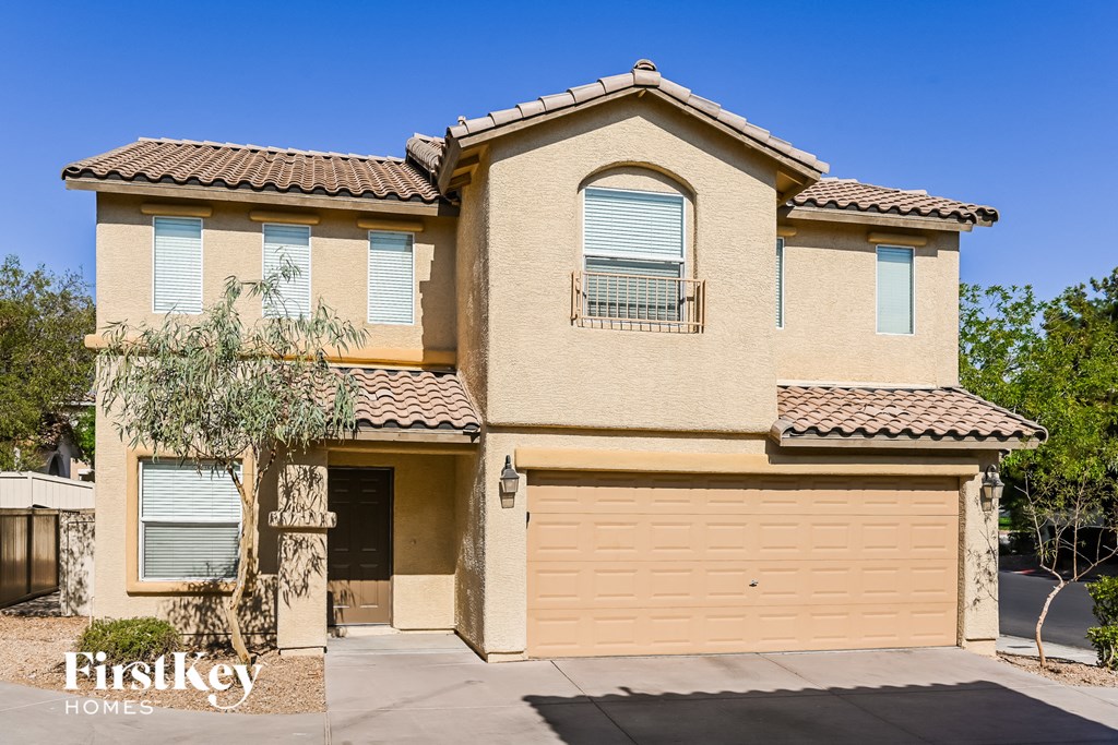 a beige house with a garage and a tree