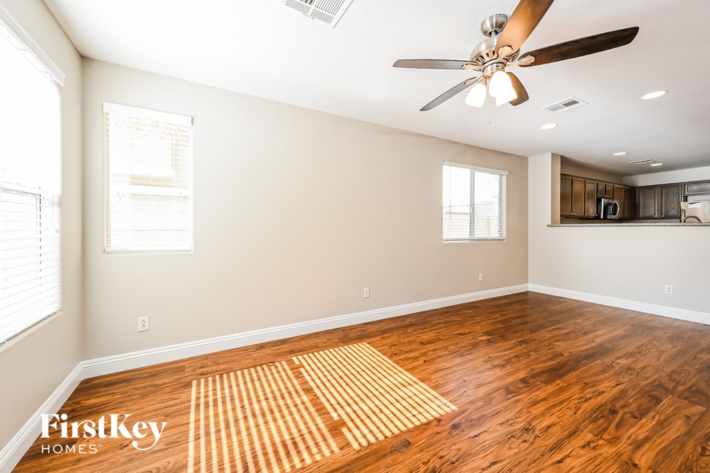 the living room and dining room with wood floors and a ceiling fan