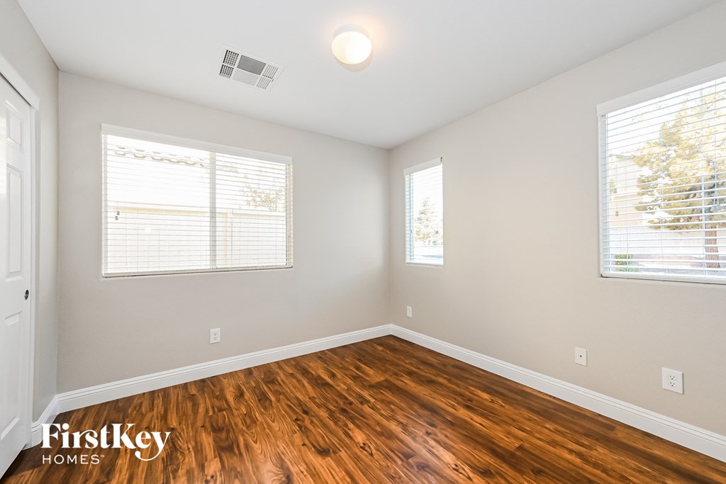 the living room of a home with wood flooring and two windows