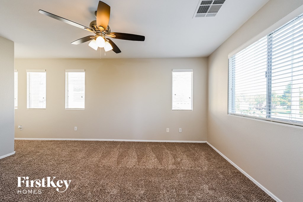 an empty living room with a ceiling fan and a window