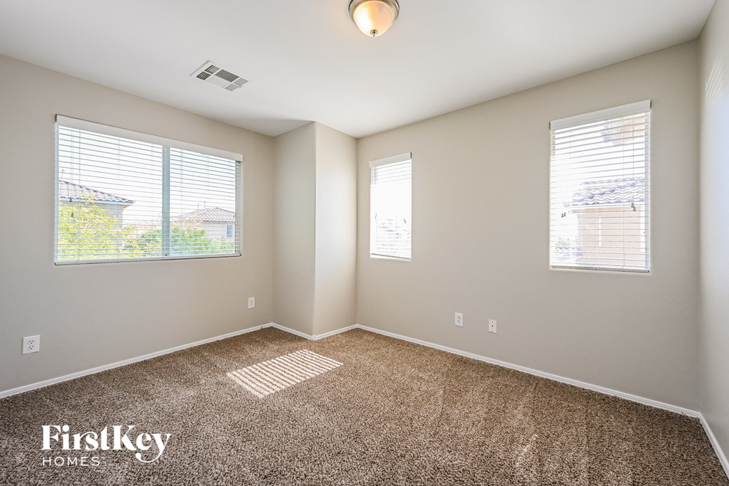 an empty room with carpet and two windows