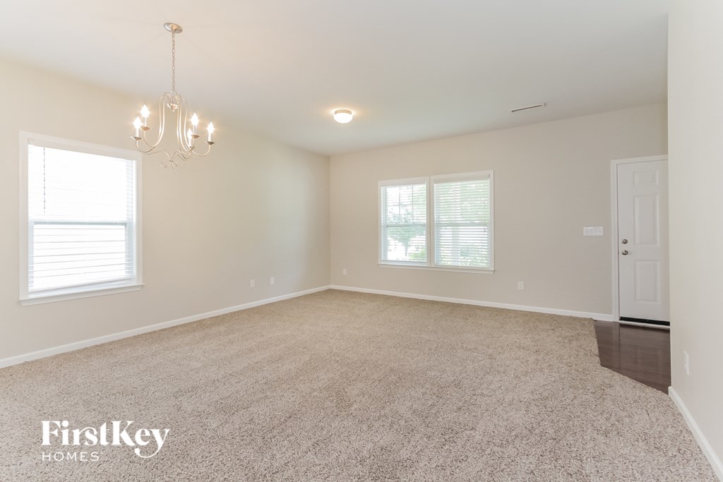 a empty living room with a chandelier and a window