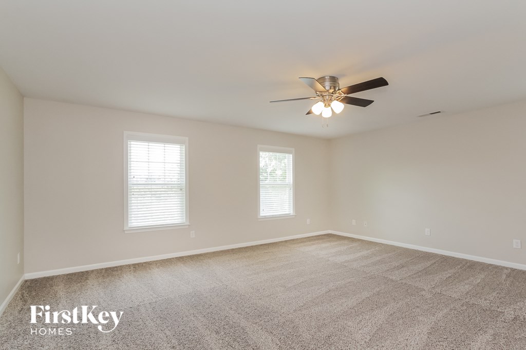 the spacious living room with ceiling fan and carpeting