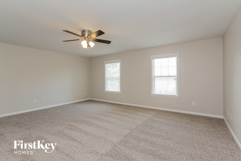 an empty living room with a ceiling fan and two windows