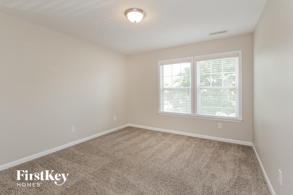 a bedroom with a carpeted floor and two windows