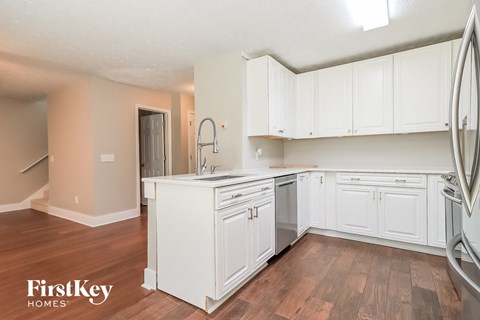 A kitchen with white cabinets and a wooden floor.