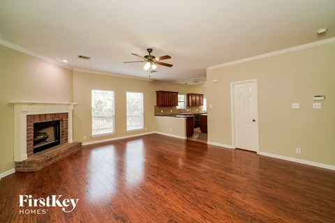 an empty living room with a fireplace and a ceiling fan