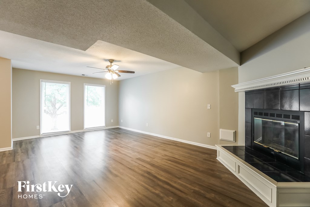 an empty living room with a fireplace and a ceiling fan