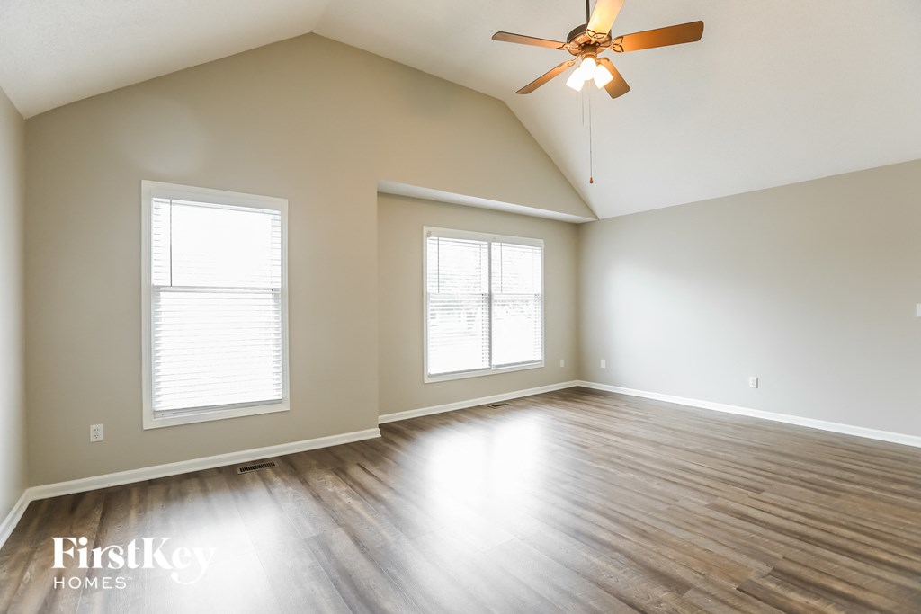 an empty living room with wood floors and a ceiling fan