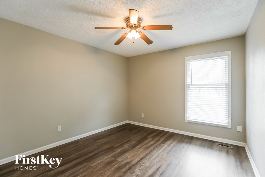 the spacious living room with hardwood flooring and a ceiling fan