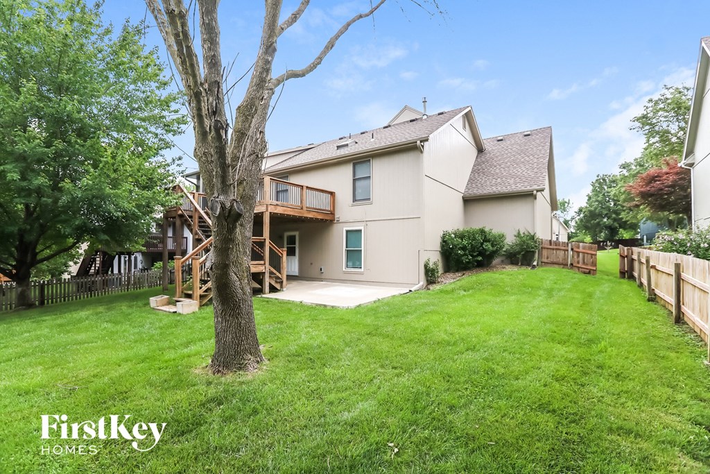 a backyard with a tree and a house with a deck