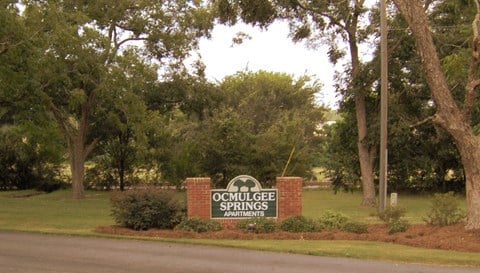 a sign that says apartments in front of some trees