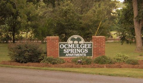 the sign for theocomlege springs apartments is in front of a brick fence