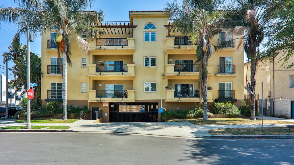a yellow apartment building with palm trees in front of it
