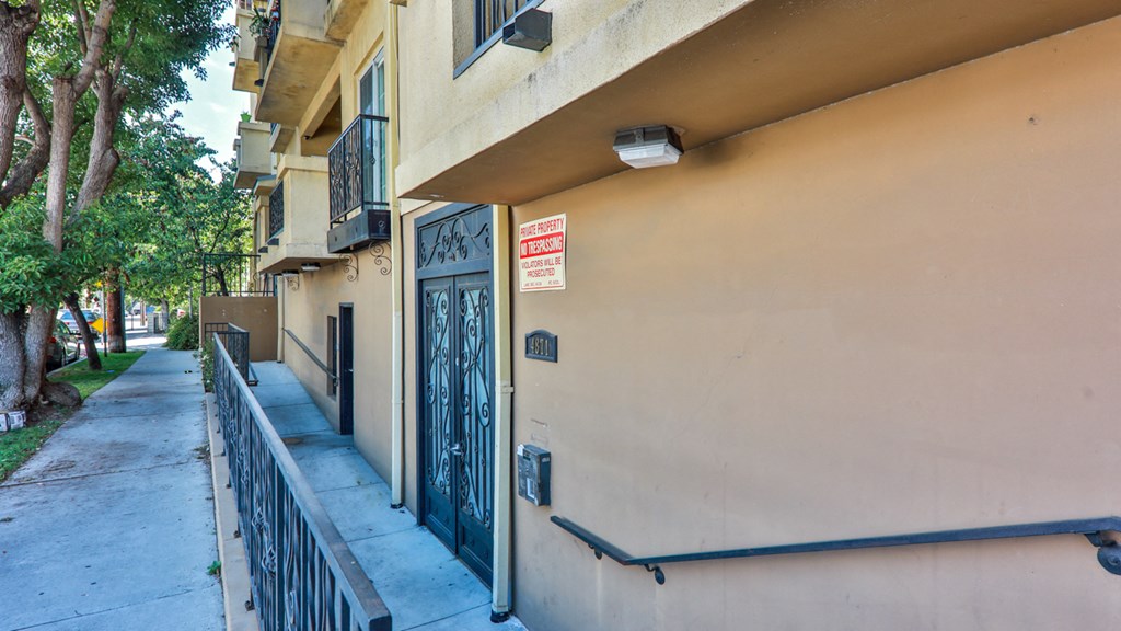 an apartment building with a sign on the door and a sidewalk
