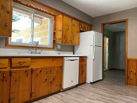 A kitchen with wooden cabinets and a white dishwasher.