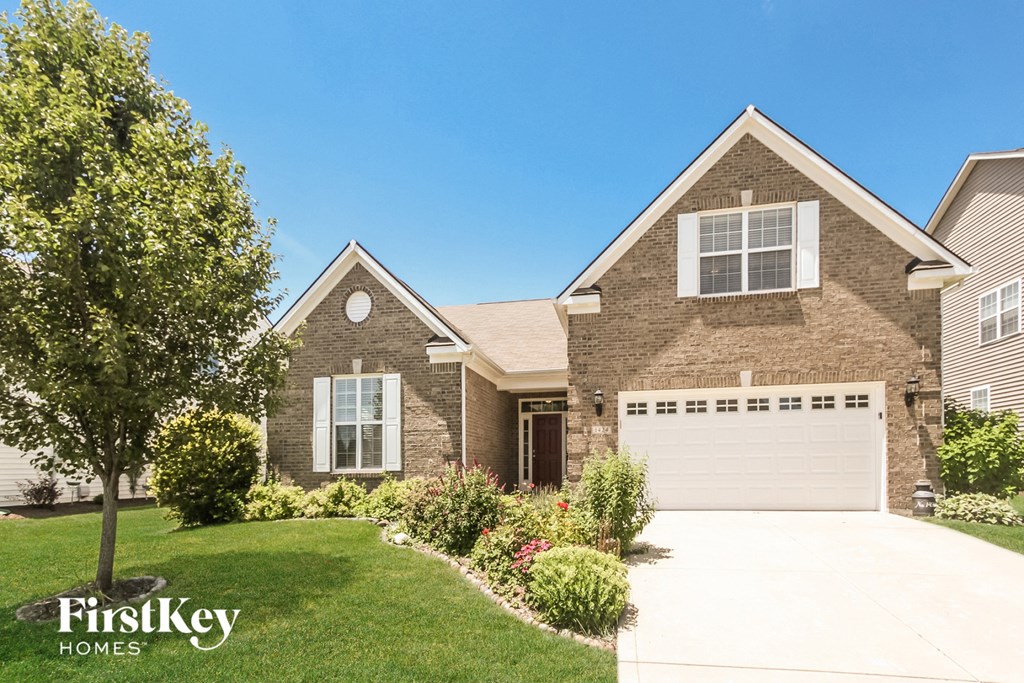 a brick house with a white garage door and a lawn