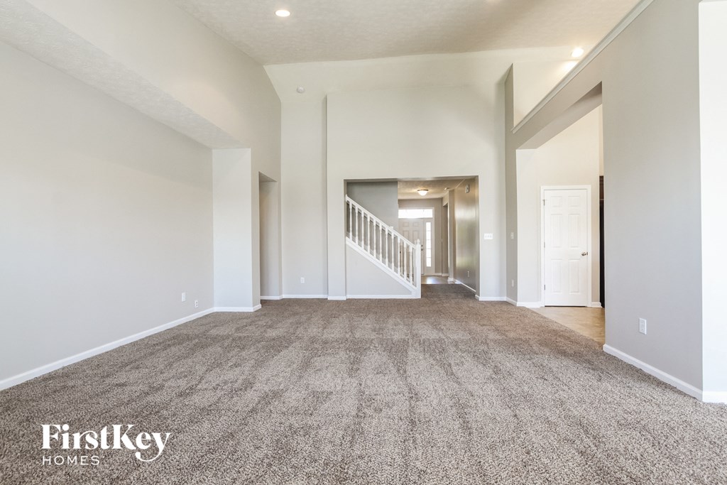 a living room with a carpeted floor and a staircase