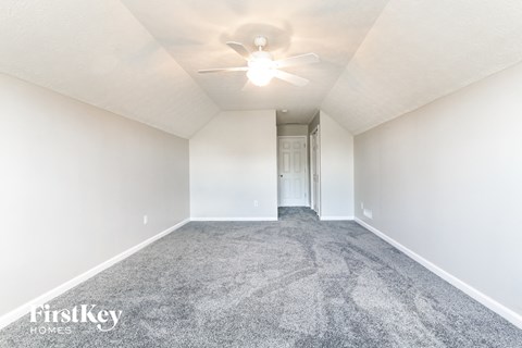 a spacious living room with carpet and a ceiling fan