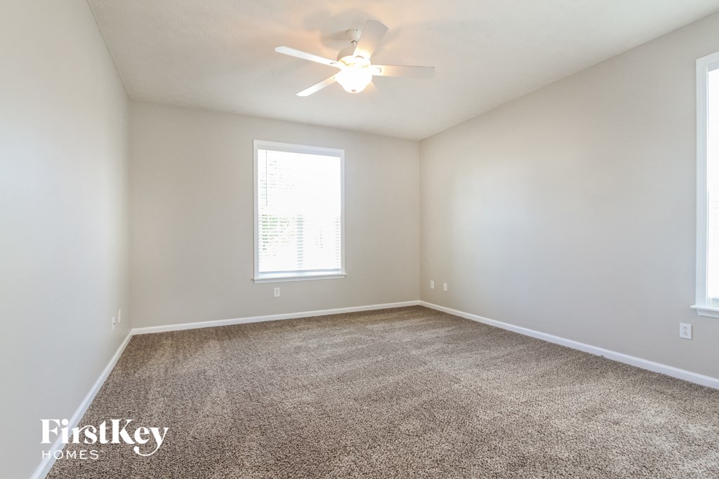 a spacious living room with carpet and a ceiling fan