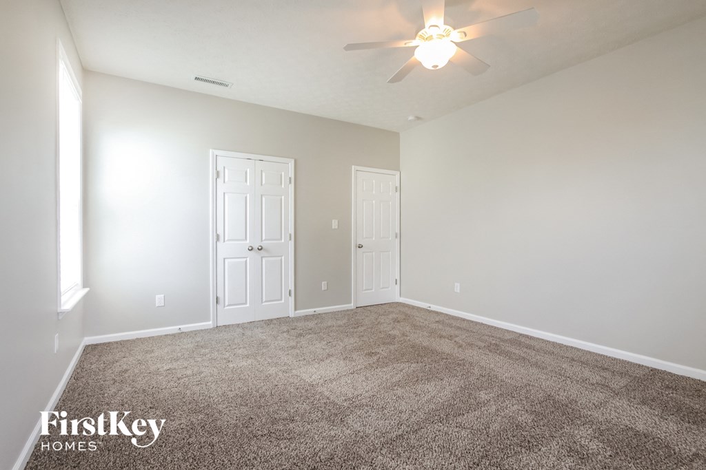 a empty living room with carpet and a ceiling fan