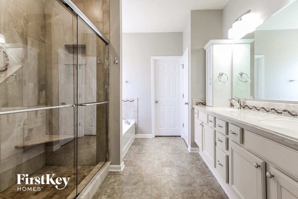 a master bathroom with a large shower and sinks and a white door