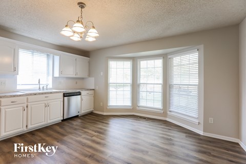 A kitchen with wooden floors and white cabinets.