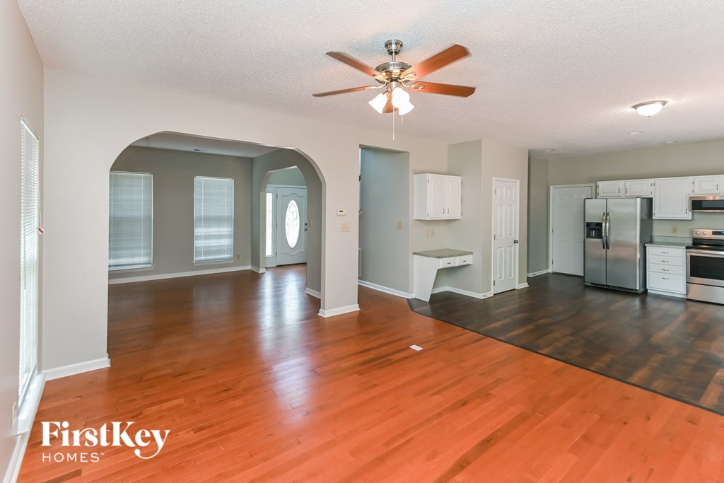 an empty kitchen and living room with wood floors and a ceiling fan