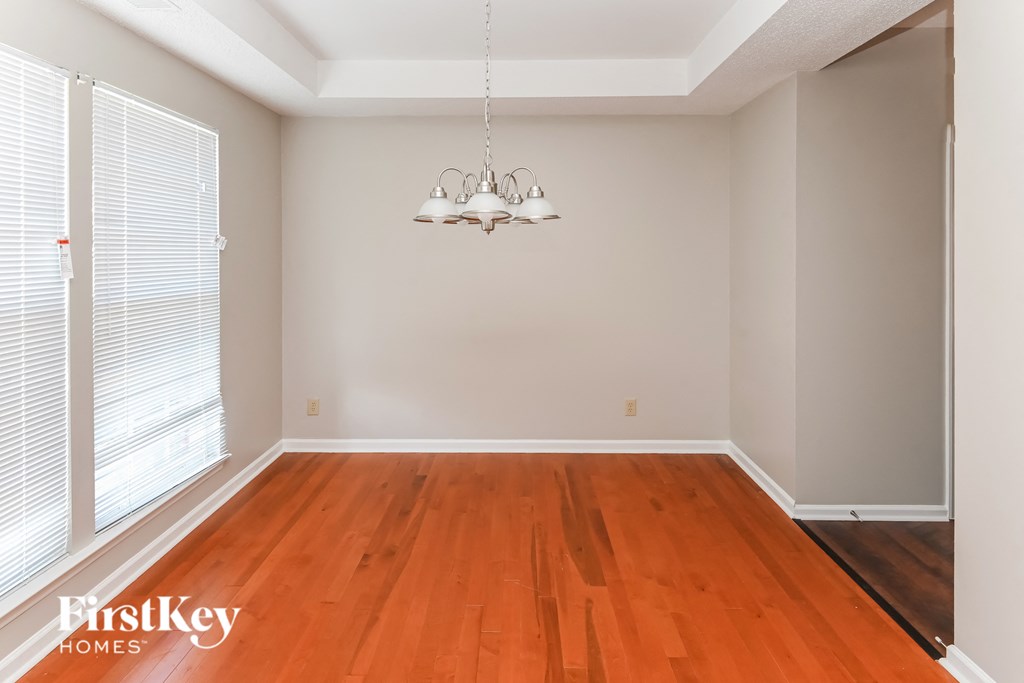 an empty dining room with wood floors and a chandelier