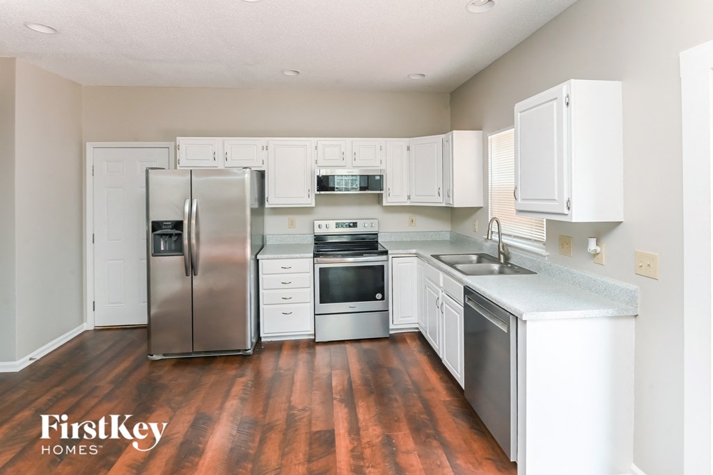 a white kitchen with stainless steel appliances and white cabinets