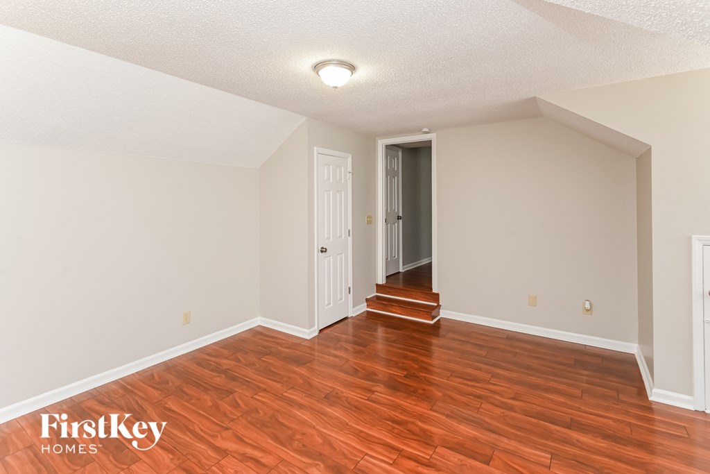 a living room with a hard wood floor and a door to a hallway